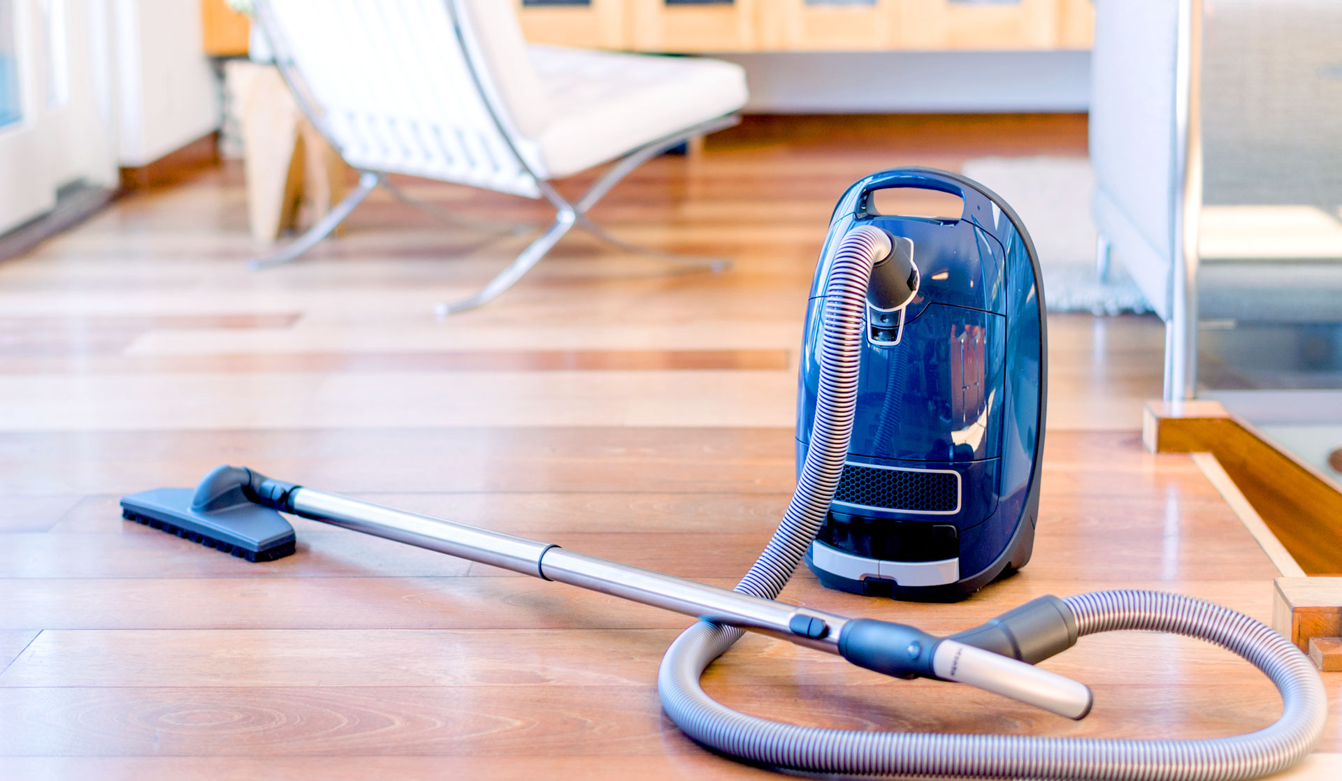 Canister vacuum on a clean floor in a sunny living room