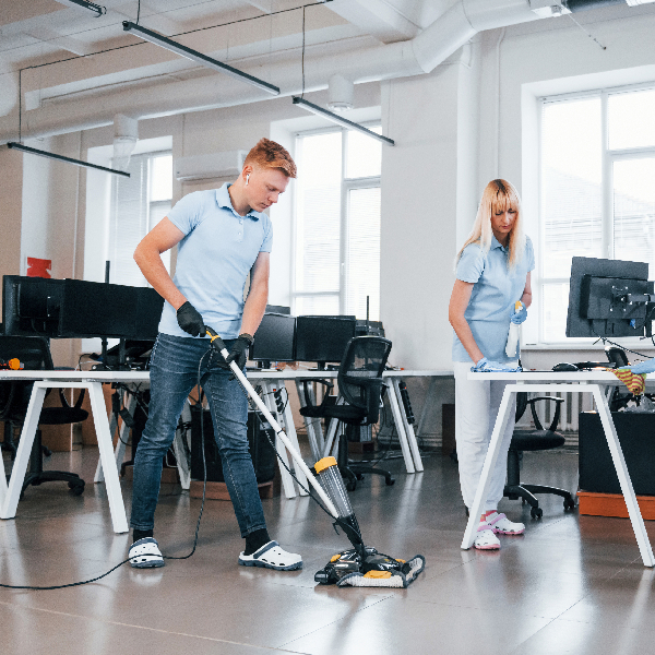 Cleaners vacuuming and tidying an open-plan office