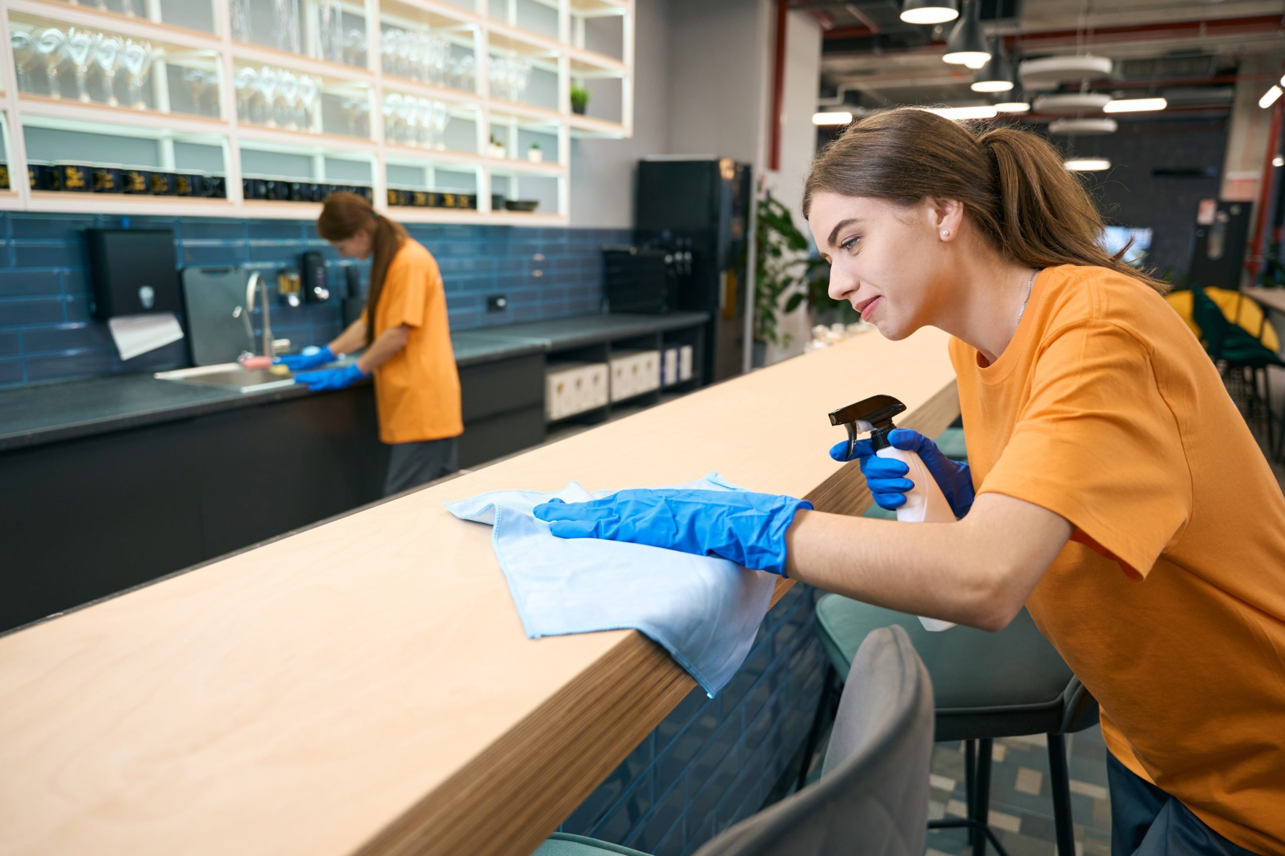 Cleaner wiping down a desk in a bright, modern office