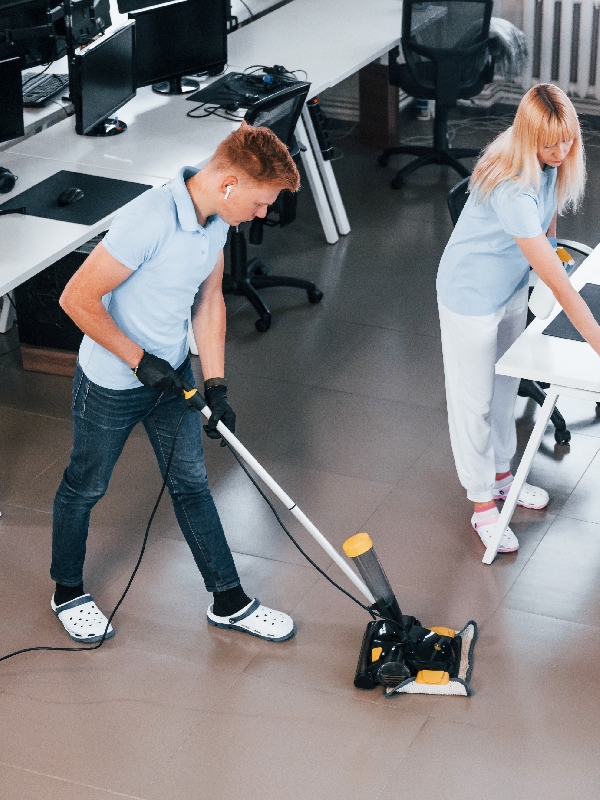 Cleaners mopping and vacuuming an office workspace