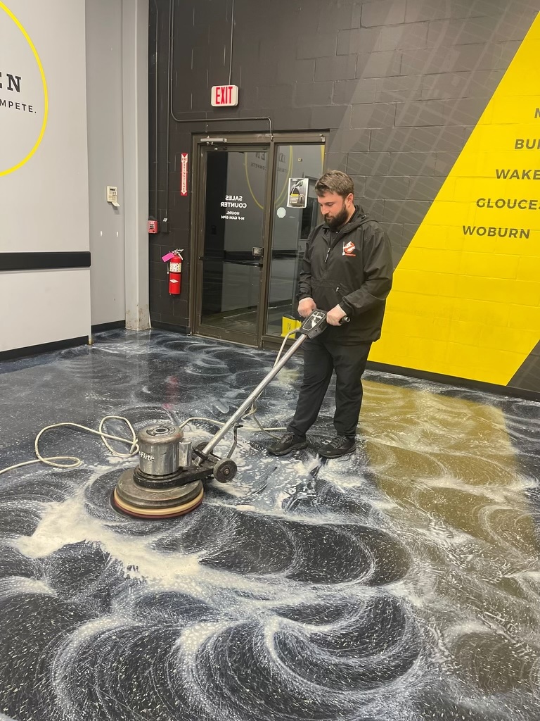 Dustbusters technician using a floor buffer to scrub a commercial floor