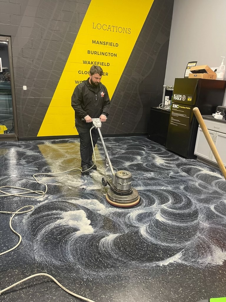 Dustbusters technician using a floor buffer in a fitness facility