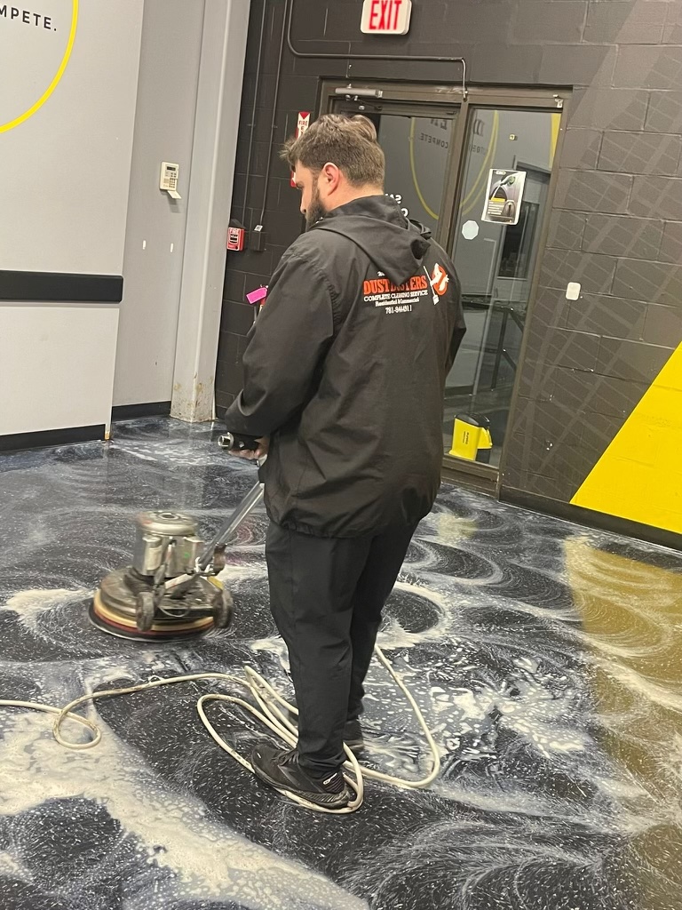 Dustbusters technician scrubbing a floor with professional equipment